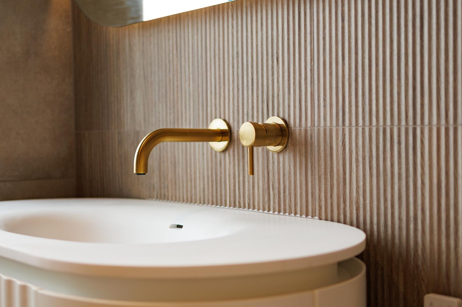 Close-up of brass wall-mounted tap with textured tile