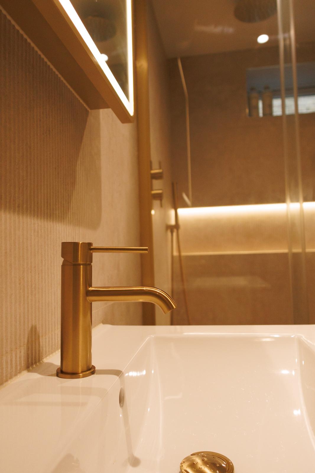 Contemporary bathroom with brass tap and warm lighting