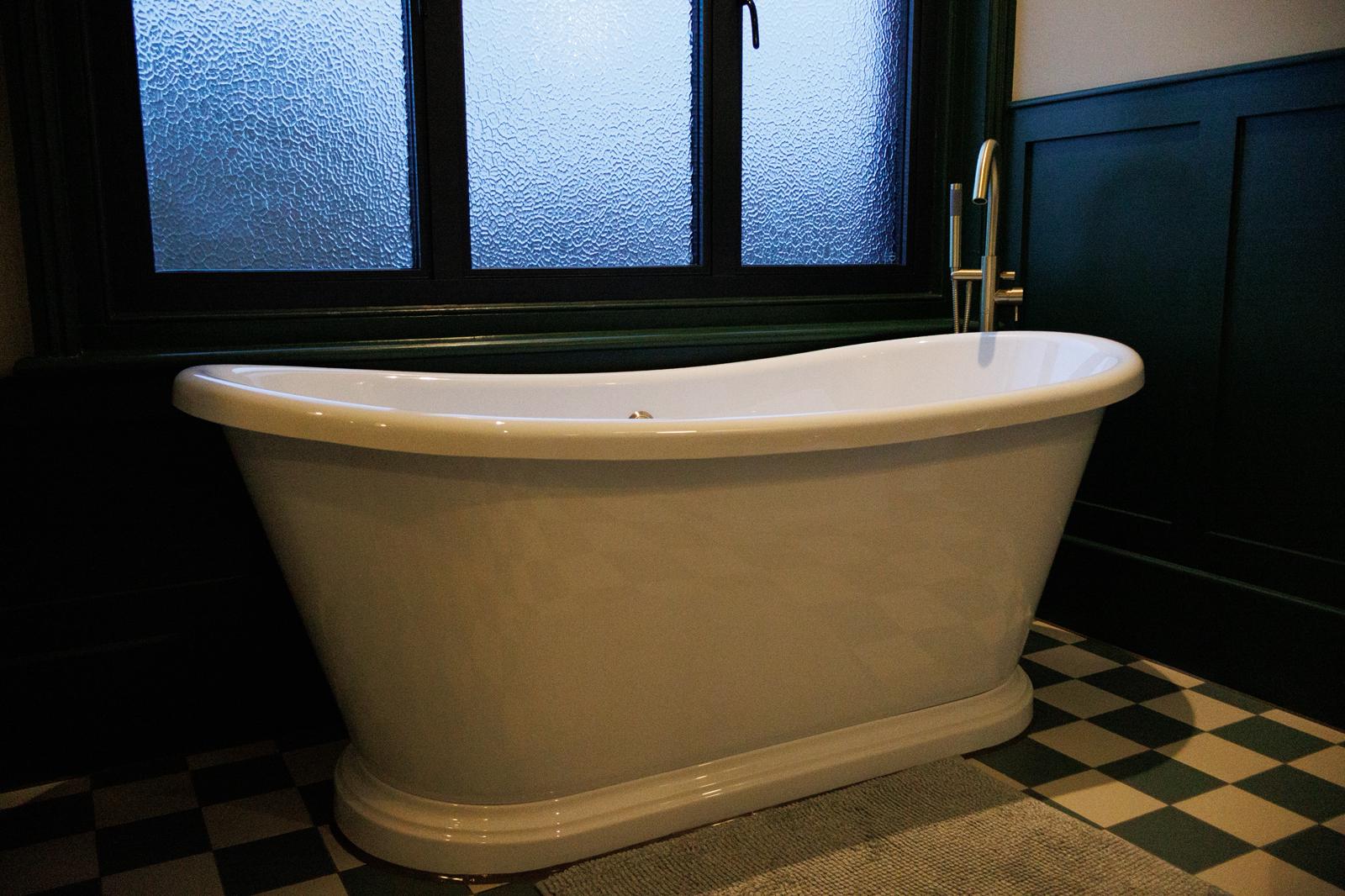 Freestanding white bathtub with brass tap